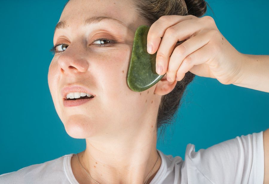 Piedra gua sha de jade sobre el rostro